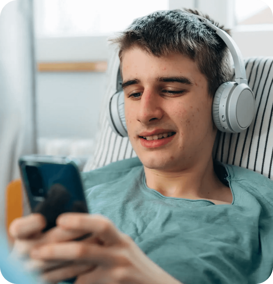 Ung man använder mobiltelefon hemma