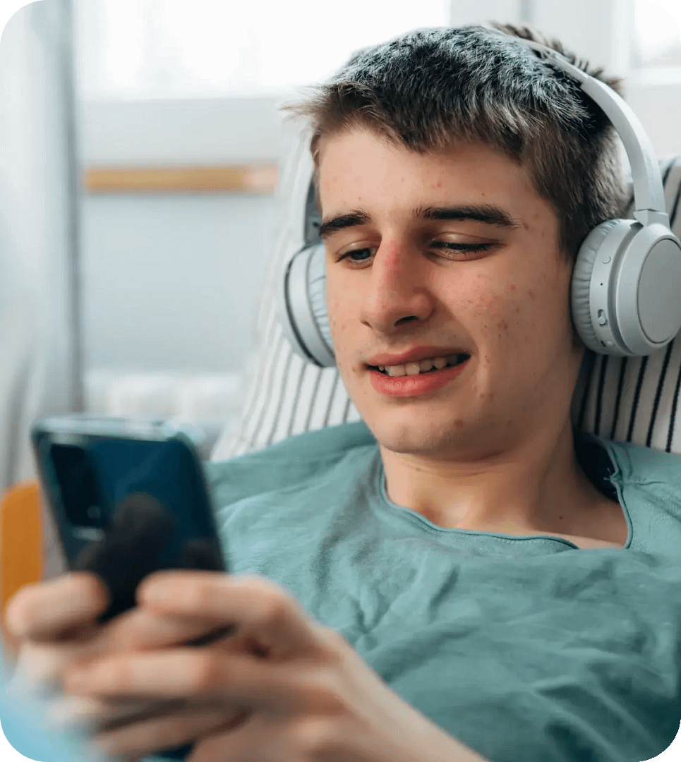 Ung man använder mobiltelefon hemma